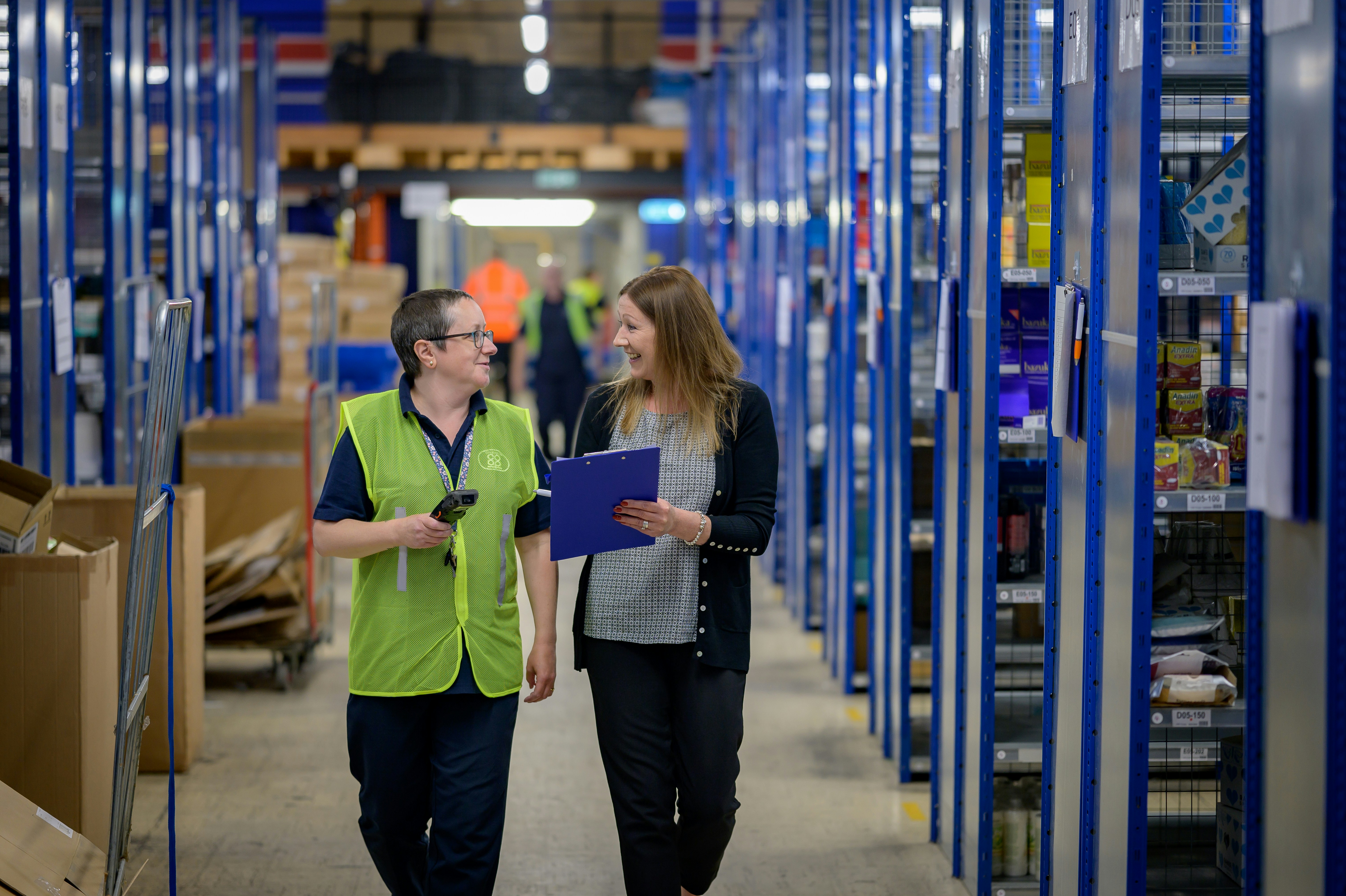 Two people walk through a warehouse smiling. Image credit, Centre for Ageing Better on Unsplash.